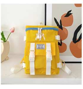 Close-up of bright yellow nylon backpack with NY embroidery and buckle strap details