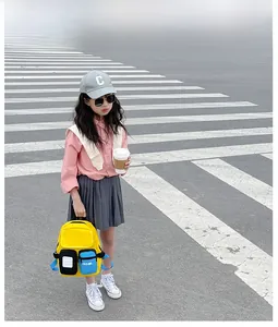 Close-up of bright yellow kids canvas backpack with blue and black pockets in street view