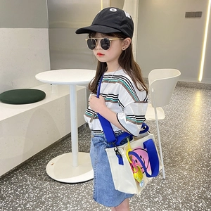 Kid's smiley canvas crossbody bag with blue straps and colorful charms in street style