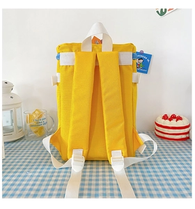 Detail of a bright yellow nylon kids backpack with white straps and adjustable buckles
