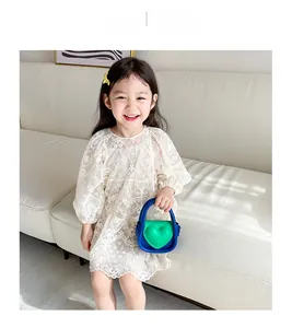 Gros plan d'une fille en robe de dentelle blanche avec un sac à main cœur bicolore