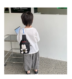 Detail showing kids black chest bag with plush bunny doll and Happy embroidery