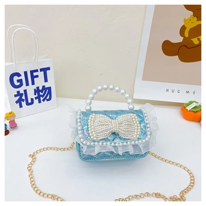 Detail of blue sequin girls handbag with pearl bow, lace trim and golden chain strap
