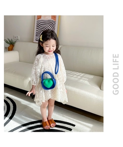 Fille en robe de dentelle portant un mini sac bandoulière bleu avec relief cœur vert