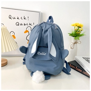 Detail of blue canvas kids backpack with cute rabbit ears and white pom-pom tail