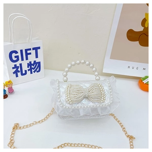 Detail of white lace mini bag with pearl bow design and elegant gold chain strap