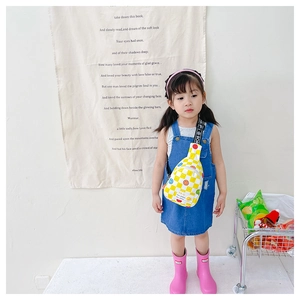 Toddler wearing yellow checkerboard sling bag with colorful smiley face print details