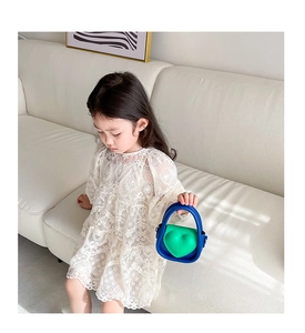 Gros plan du mini sac bicolore bleu et vert avec cœur tenu par une petite fille en dentelle