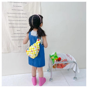 Close-up of yellow checkered kids chest bag with smiley face worn by a little girl