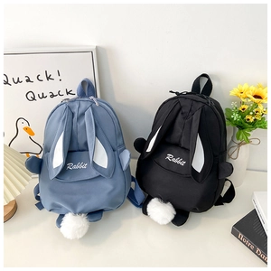Detail of blue and black rabbit-themed canvas backpacks with cute ears and fluffy pom-pom tails