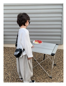 Détail d'un sac à bandoulière rond noir pour enfant avec imprimé lettres blanches