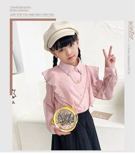 Detail of pink ruffled shirt with pearl button and gold chain on girls outfit