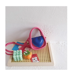 Détail du mini sac en cuir PU rose et bleu avec cœur dans un plateau en bois