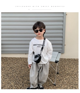 Détail de la tenue pour garçon avec un t-shirt blanc à manches longues et un pantalon gris