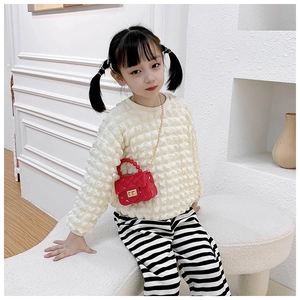 Girl's red PVC quilted jelly bag with pearl handle and gold chain worn by a model