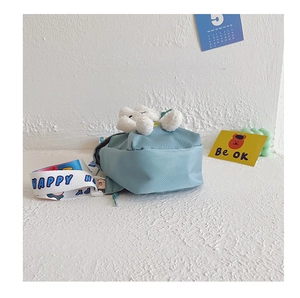 Detail of light blue nylon kids bag with 3D white plush bear and Happy printed strap