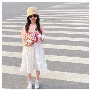 Outdoor shot of a girl wearing an orange checkered crossbody bag with smiley face patterns