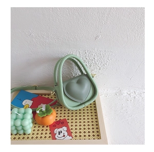 Détail d'un mini sac fille vert clair en forme de cœur avec motif gaufré et bandoulière