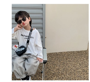 Détail d'un sac bandoulière noir avec lettrage SUP sur un garçon au look urbain cool