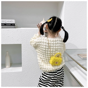 Kids quilted yellow jelly bag with pearl handle shown on minimalist white display stand