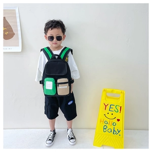 Detail of child backpack with green straps and fashion lettered pockets in studio setting