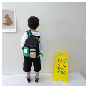 Close-up of kids black canvas backpack featuring green side pockets and adjustable straps