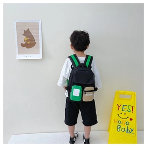 Rear view of child wearing contrast color canvas backpack with bright green straps