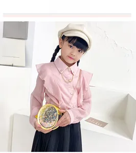 Detail of pink long-sleeved girl shirt featuring ruffled chest and gold chain collar
