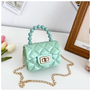Macro detail of mint green quilted jelly bag with bead handle and gold chain strap