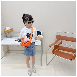 Gros plan du sac cylindre orange vif avec texte Limerance porté par un enfant mannequin