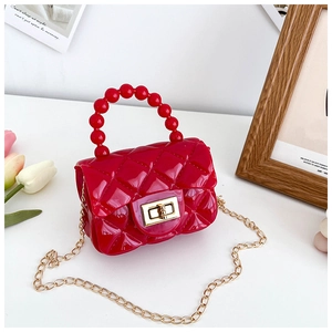 Detail of red quilted PVC jelly bag with pearl handle and golden chain strap