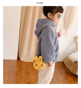 Detail of cute yellow plush bunny crossbody bag with embroidery on a child model