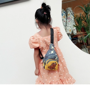 Sac de poitrine enfant motif dinosaure en toile bleue porté par un petit garçon