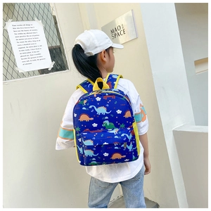 Rear view of a child wearing a dark blue backpack with colorful cartoon dinosaur prints