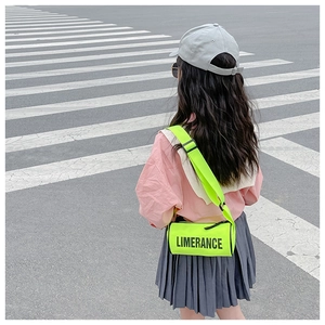 Photo extérieure d'un enfant portant un sac cylindre jaune néon avec lettrage noir