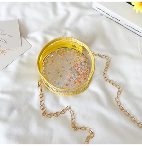 Detail of round transparent bag with colorful sequins and golden chain strap