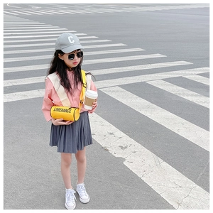 Détail du sac cylindrique jaune pour enfant porté avec chemise rose et jupe grise