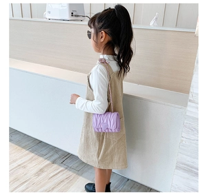 Girl's purple heart-quilted crossbody bag with a braided chain strap shown on model