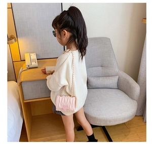 Pink heart quilted girls crossbody bag with gold chain strap shown on child model
