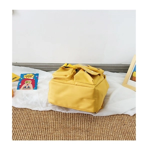 Flat lay detail of a bright yellow nylon toddler backpack with external storage pockets
