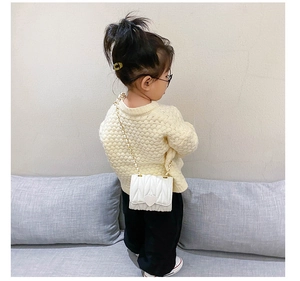 Rear view of a child wearing a white quilted crossbody bag with heart buckle and chain