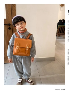 Close-up of child wearing vintage orange brown PU leather backpack with gold buckles