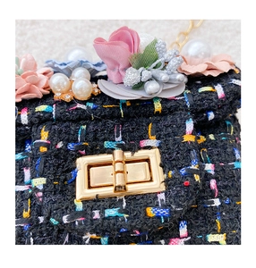 Gros plan d'un sac bandoulière en tweed pour filles avec fleurs et fermoir doré