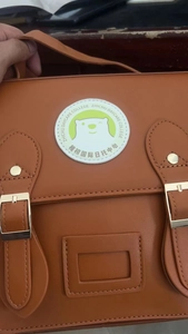 Detail of caramel PU leather school bag with dual metal buckles and round bear logo