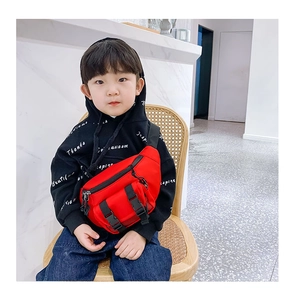 Close-up of bright red kids' crossbody chest bag with black buckles and mesh pocket