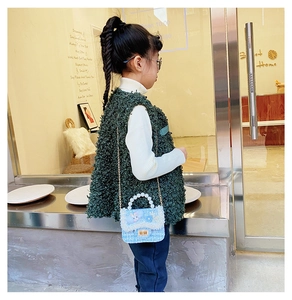 Close-up of cute blue tweed girls' crossbody bag with pearl handle and cartoon rabbit