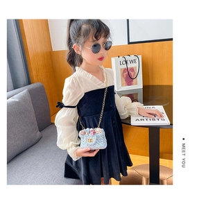 Détail du sac floral en tweed bleu avec perles et une robe de fille noire et blanche