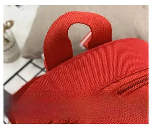 Close-up of a durable red backpack featuring a reinforced handle and smooth zipper detail