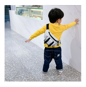Close-up of a child wearing a white minimalist crossbody bag over a yellow sweater
