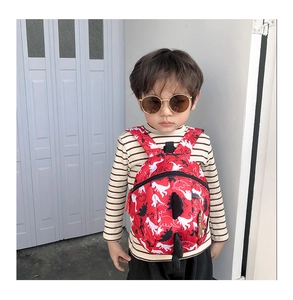 Toddler backpack with 3D dinosaur fins and pattern worn by a boy in studio